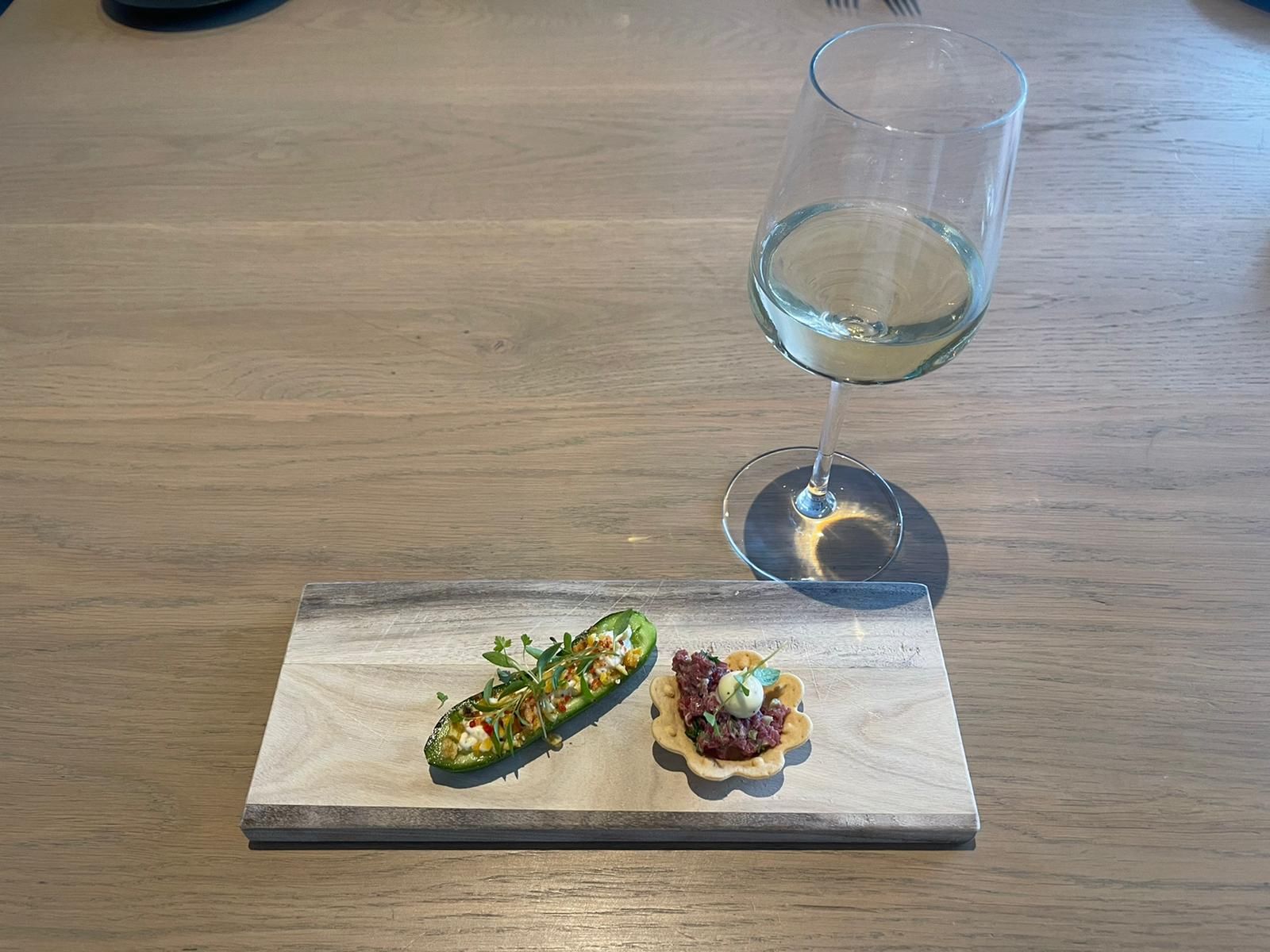 Een bord met eten en een glas wijn op een houten tafel.