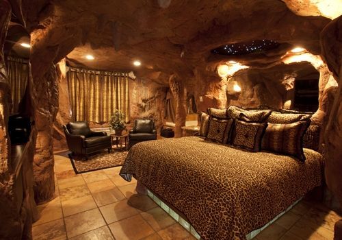 A bedroom in a cave with a bed and chairs