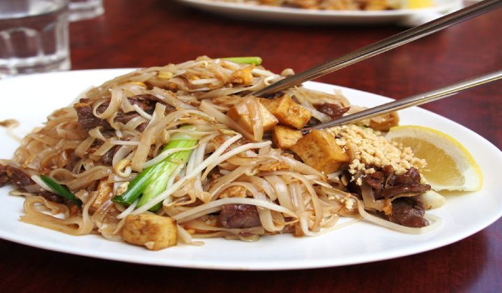 A close up of a plate of food with chopsticks on a table.