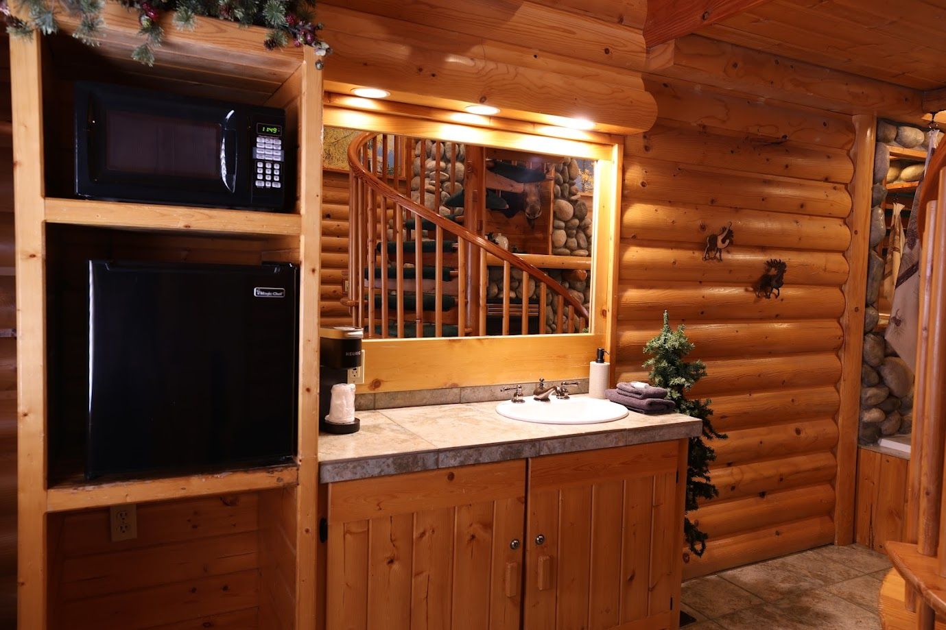 A kitchen in a log cabin with a sink , microwave , and refrigerator.