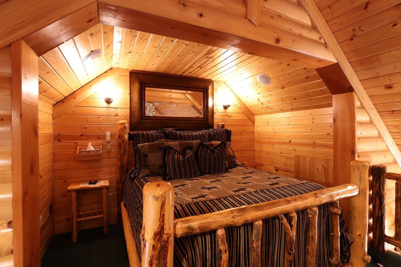 There is a bed in the attic of a log cabin.