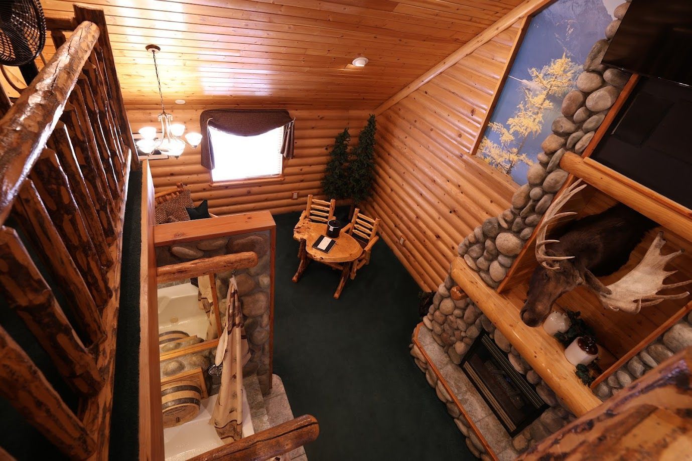 An aerial view of a log cabin with a fireplace and stairs