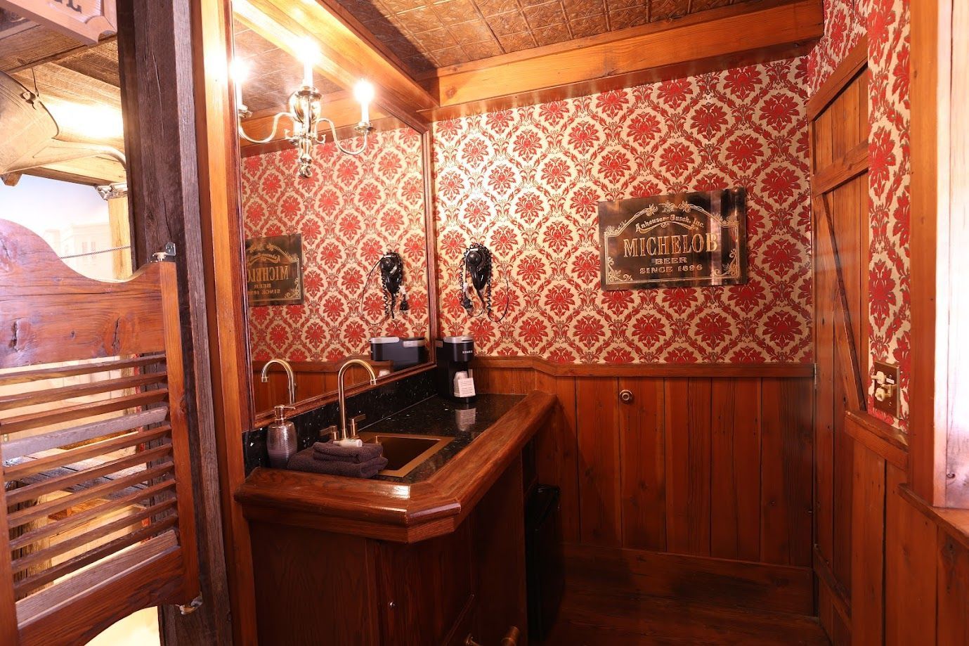 A bathroom with a sink , mirror , and red wallpaper.