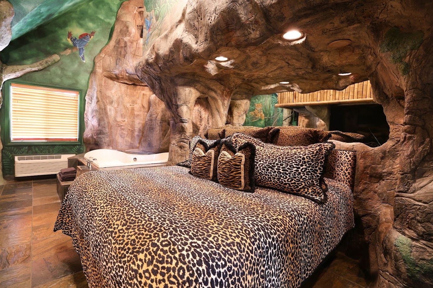 A bedroom with a leopard print bed and pillows in a cave.