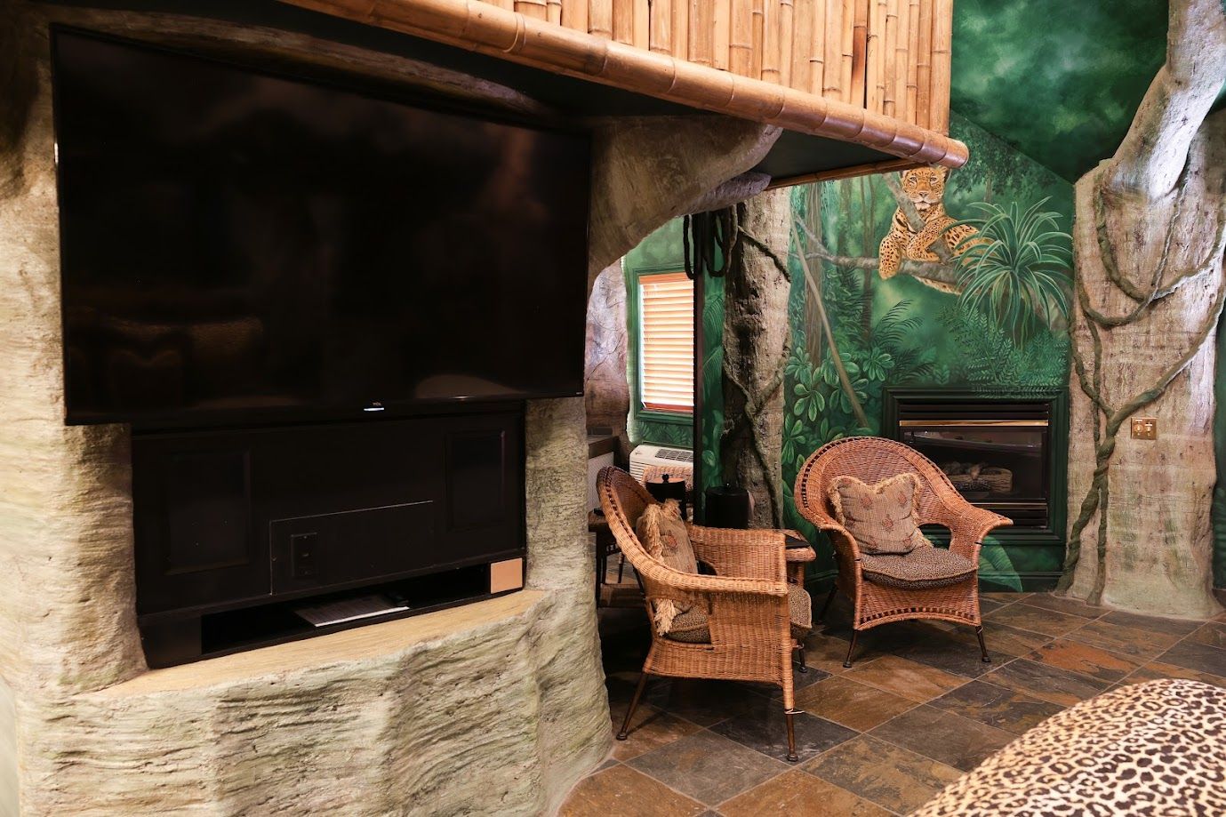 A living room with wicker chairs and a flat screen tv.