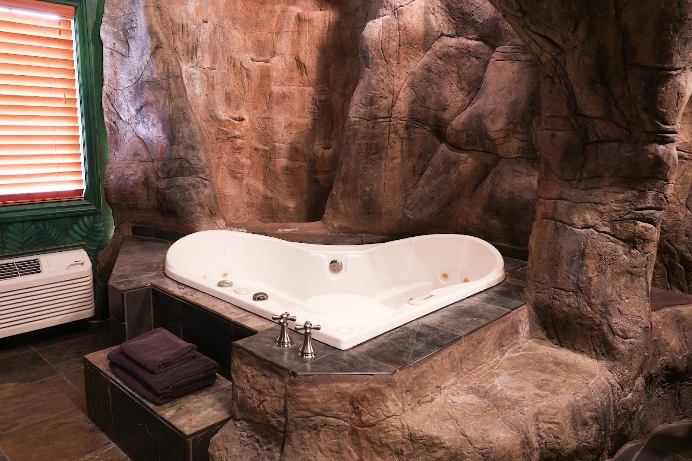 A jacuzzi tub is surrounded by rocks in a cave.