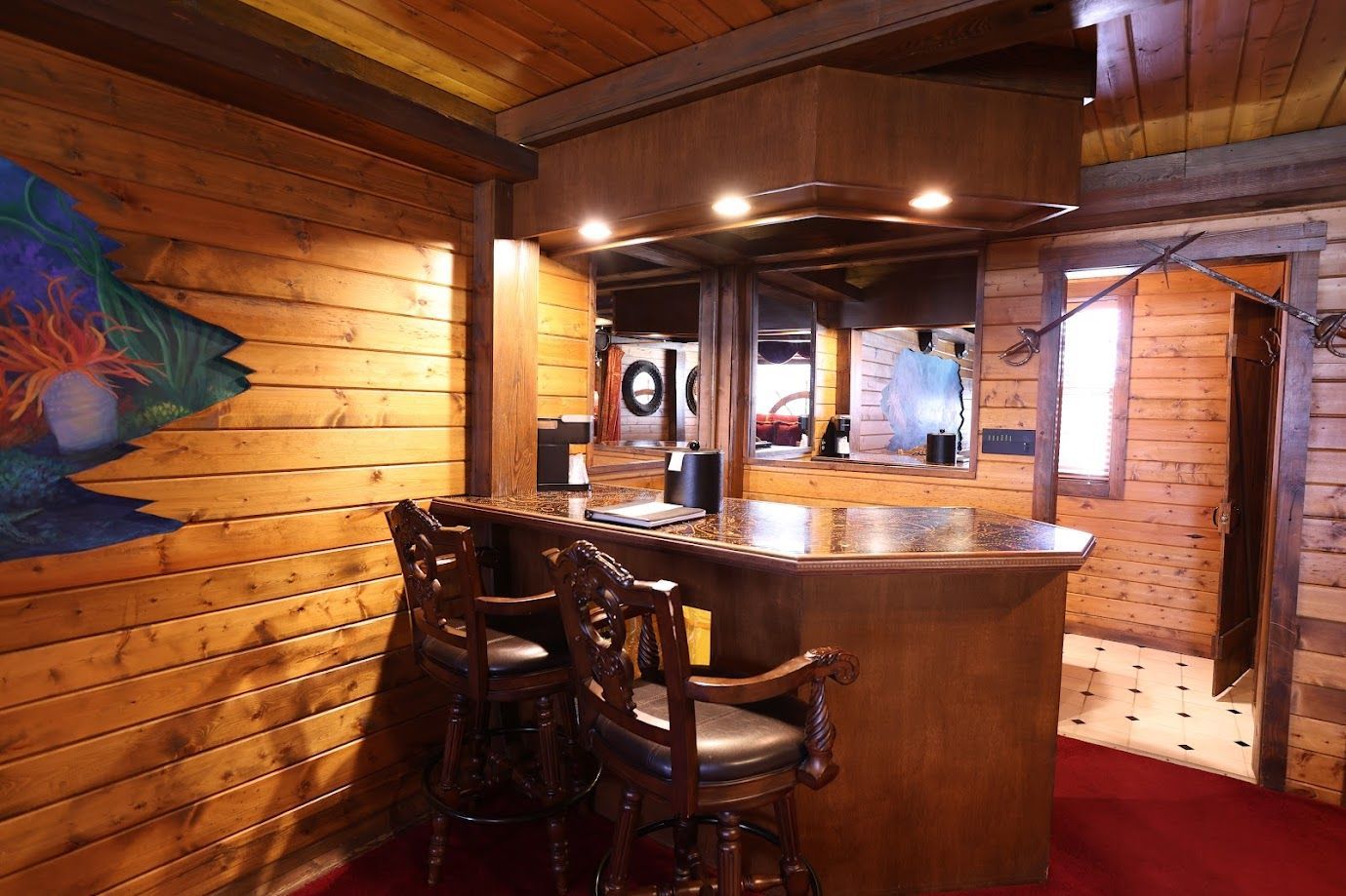 A wooden room with a bar and chairs and a painting on the wall.