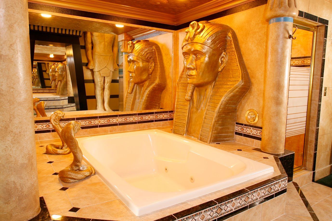 A bathroom with a jacuzzi tub and statues of pharaohs