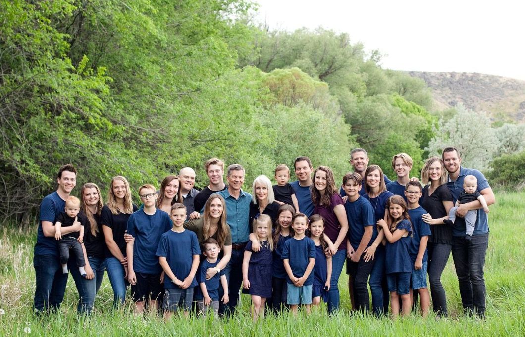 A large family is posing for a picture in a field.