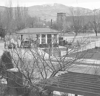 A black and white photo of a gas station with mountains in the background
