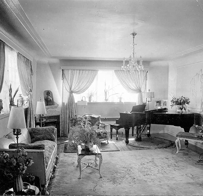 A black and white photo of a living room with a piano