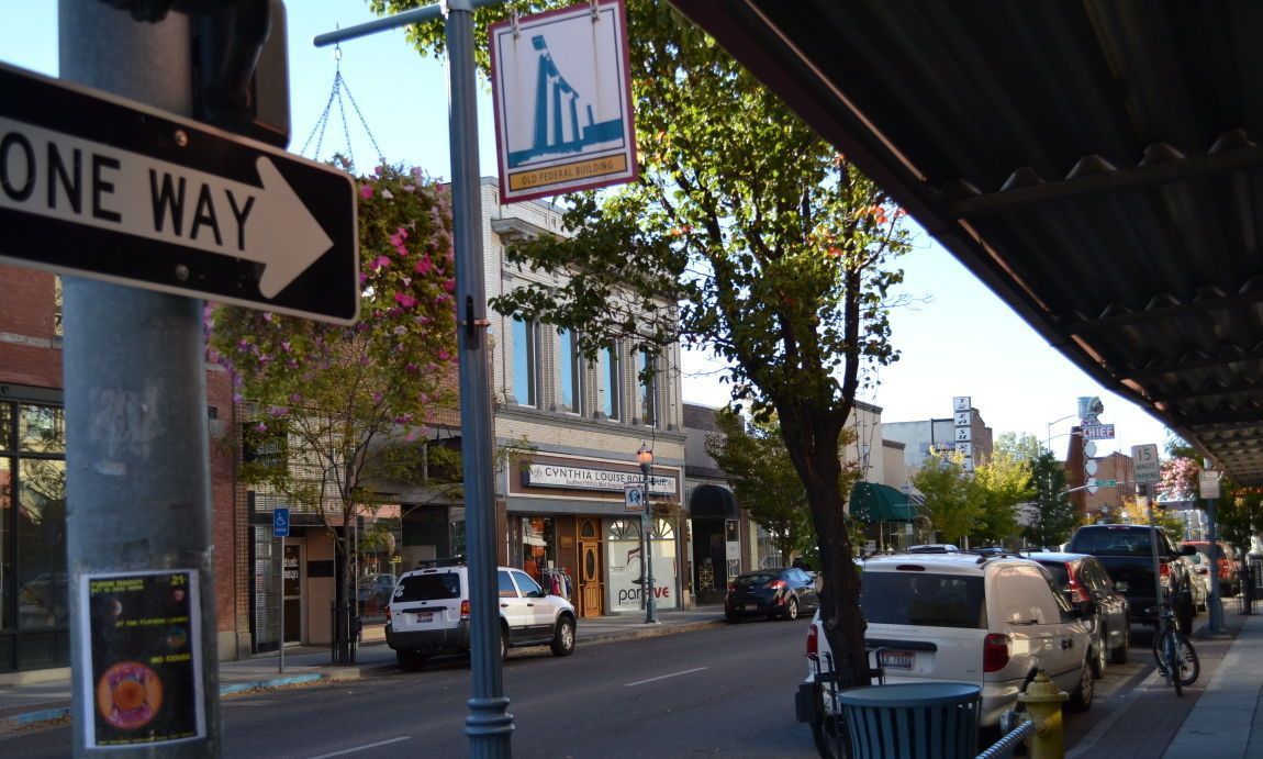 A one way street sign is hanging from a pole