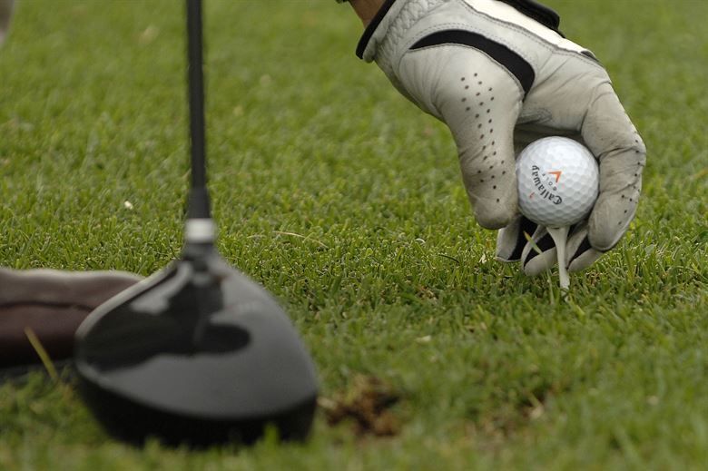 A person is putting a golf ball on a tee.