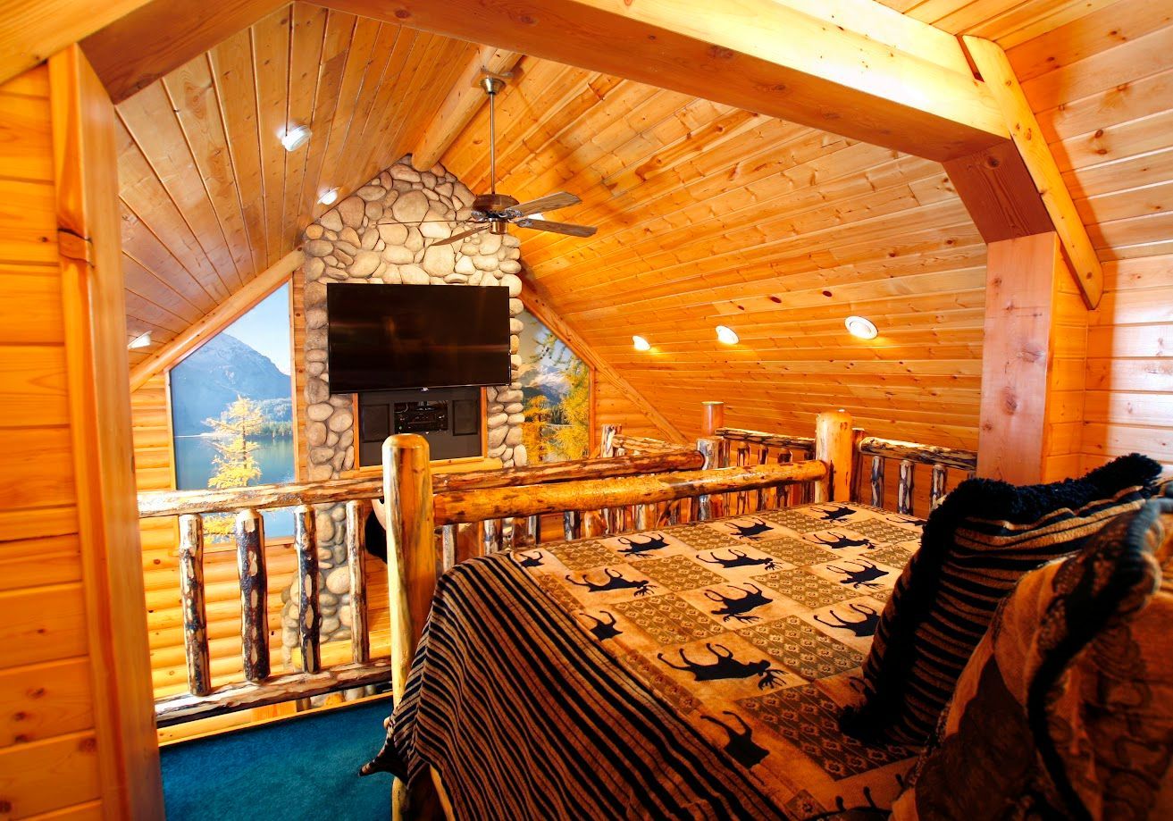 A bedroom in a log cabin with a bed and a flat screen tv