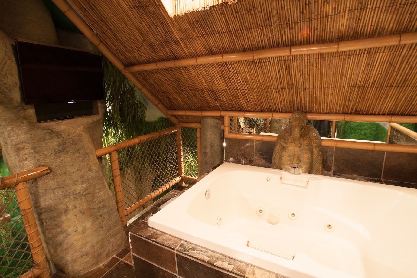 A jacuzzi tub in a bathroom with a thatched roof.