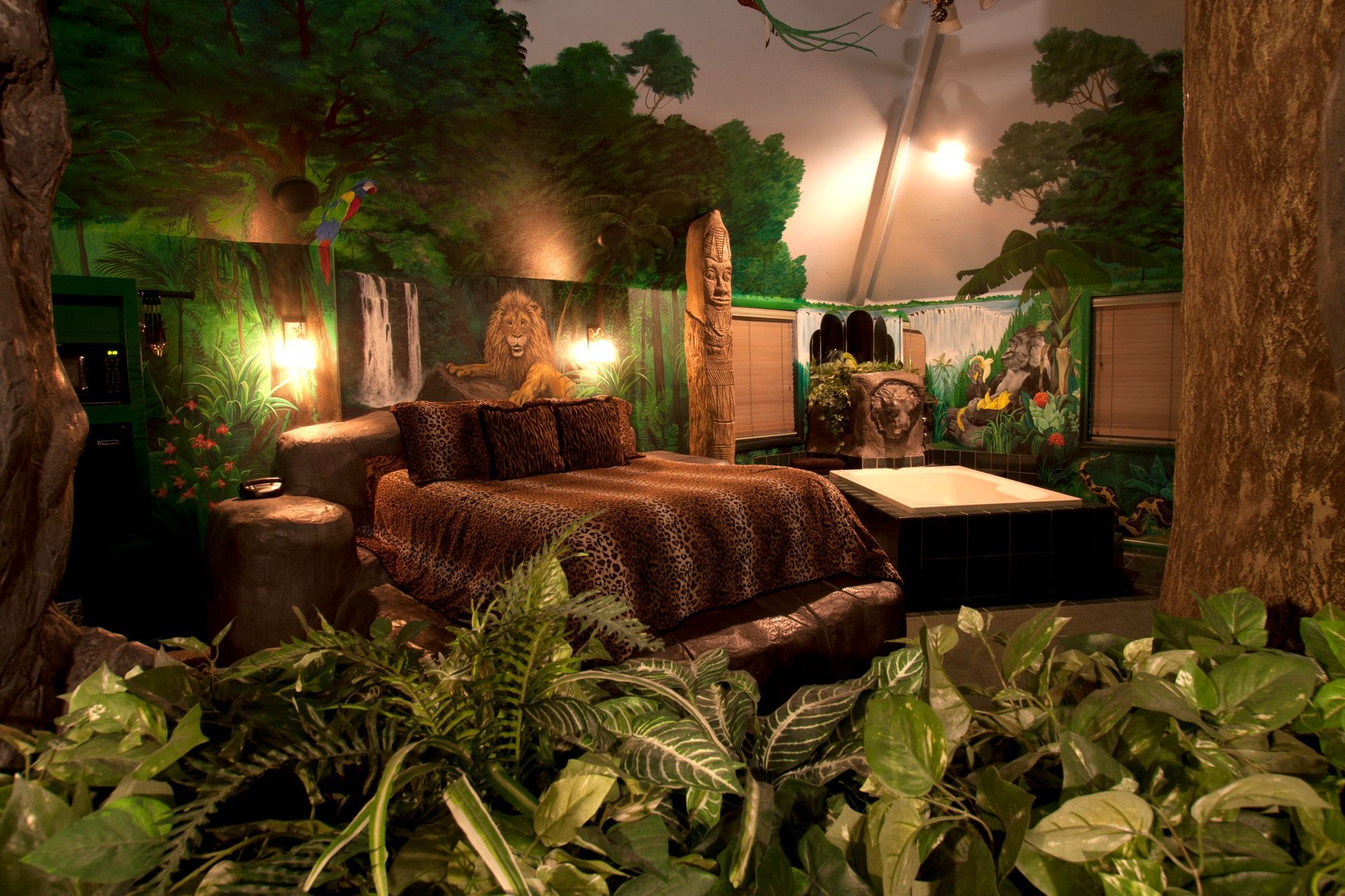 A bedroom with a bed and a painting of a jungle on the wall.