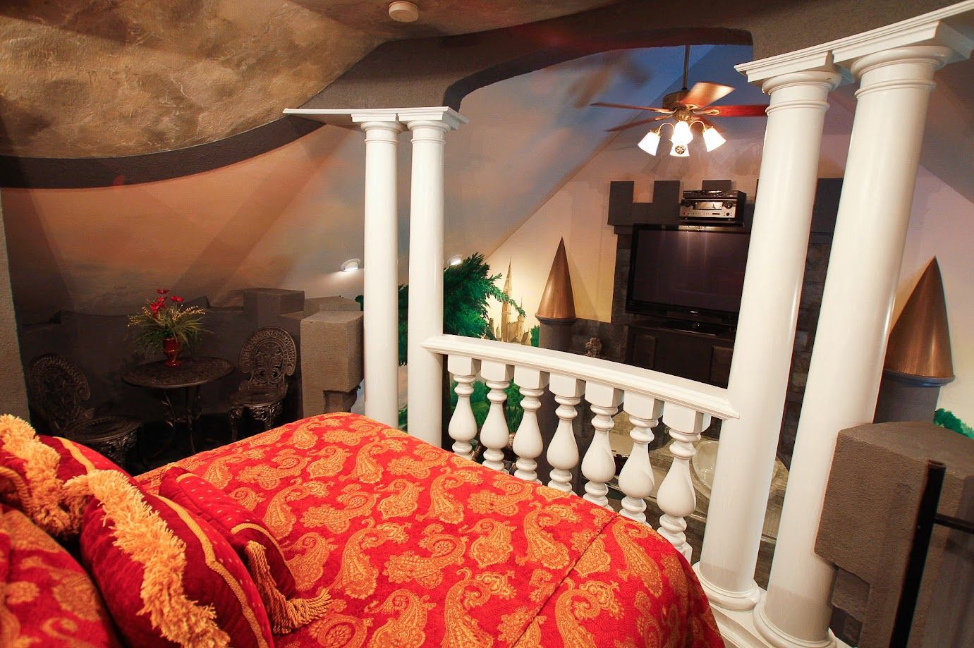 A bed in a room with columns and a ceiling fan