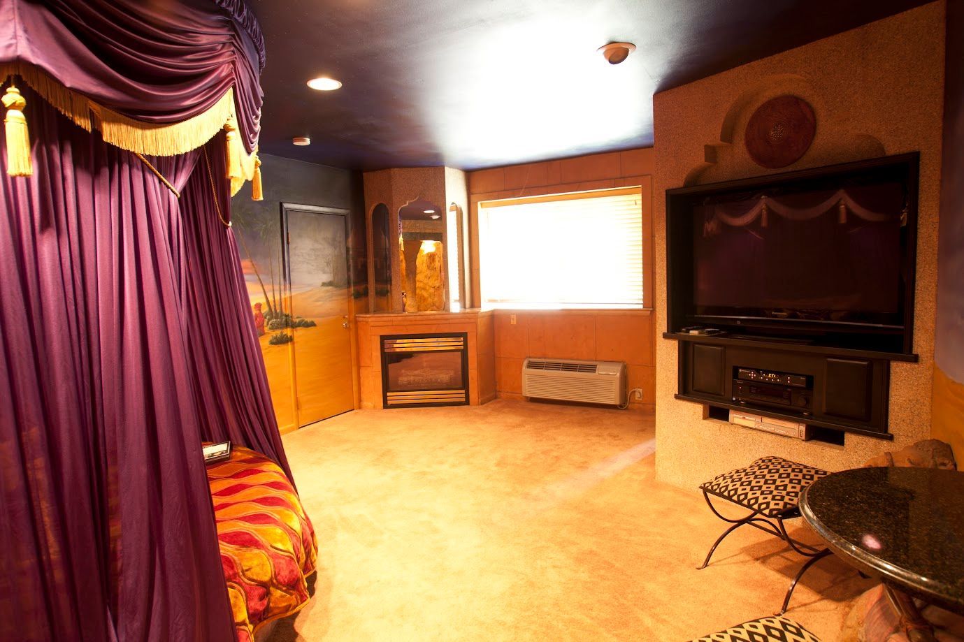 A bedroom with a purple canopy and a flat screen tv