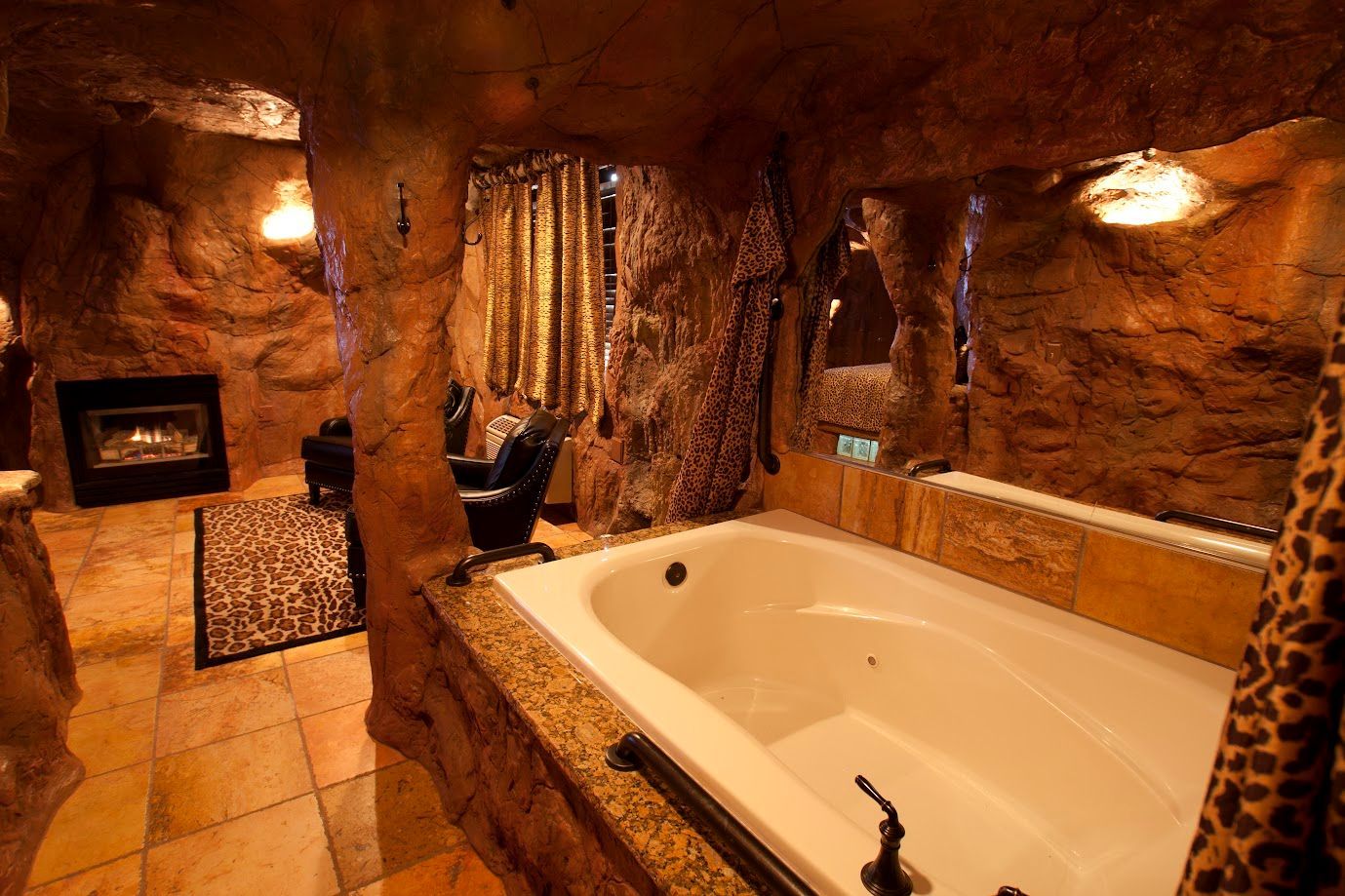 A bathtub in a cave with a leopard print curtain