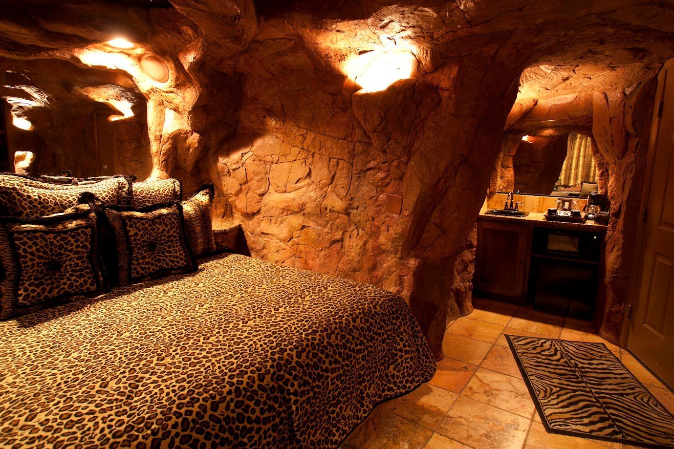 A bedroom in a cave with a leopard print bed
