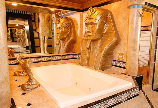 A bathroom with a bathtub and statues of pharaohs