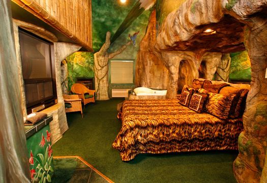 A bedroom with a bed and a tree in the ceiling.