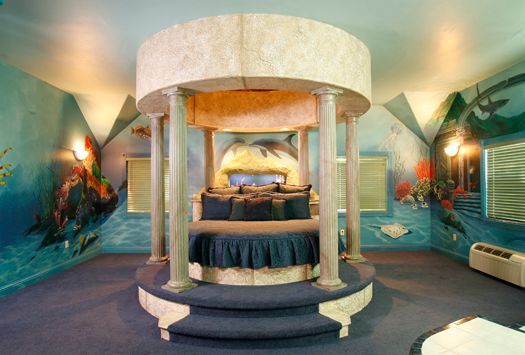 A bedroom with a round bed and dolphins painted on the walls.