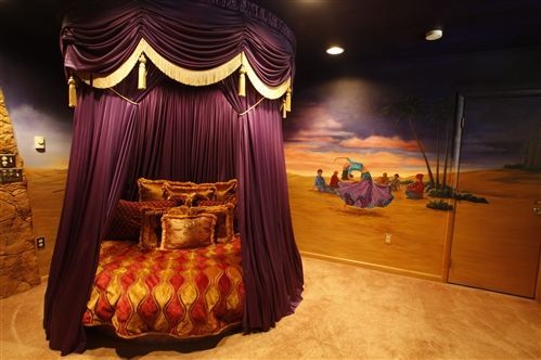 A bed with a purple canopy and a painting on the wall behind it