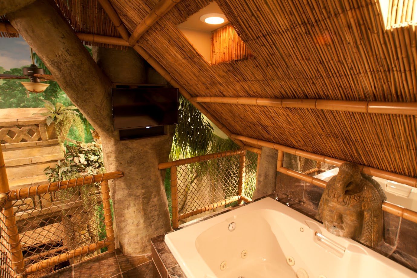 A bathroom with a jacuzzi tub under a thatched roof