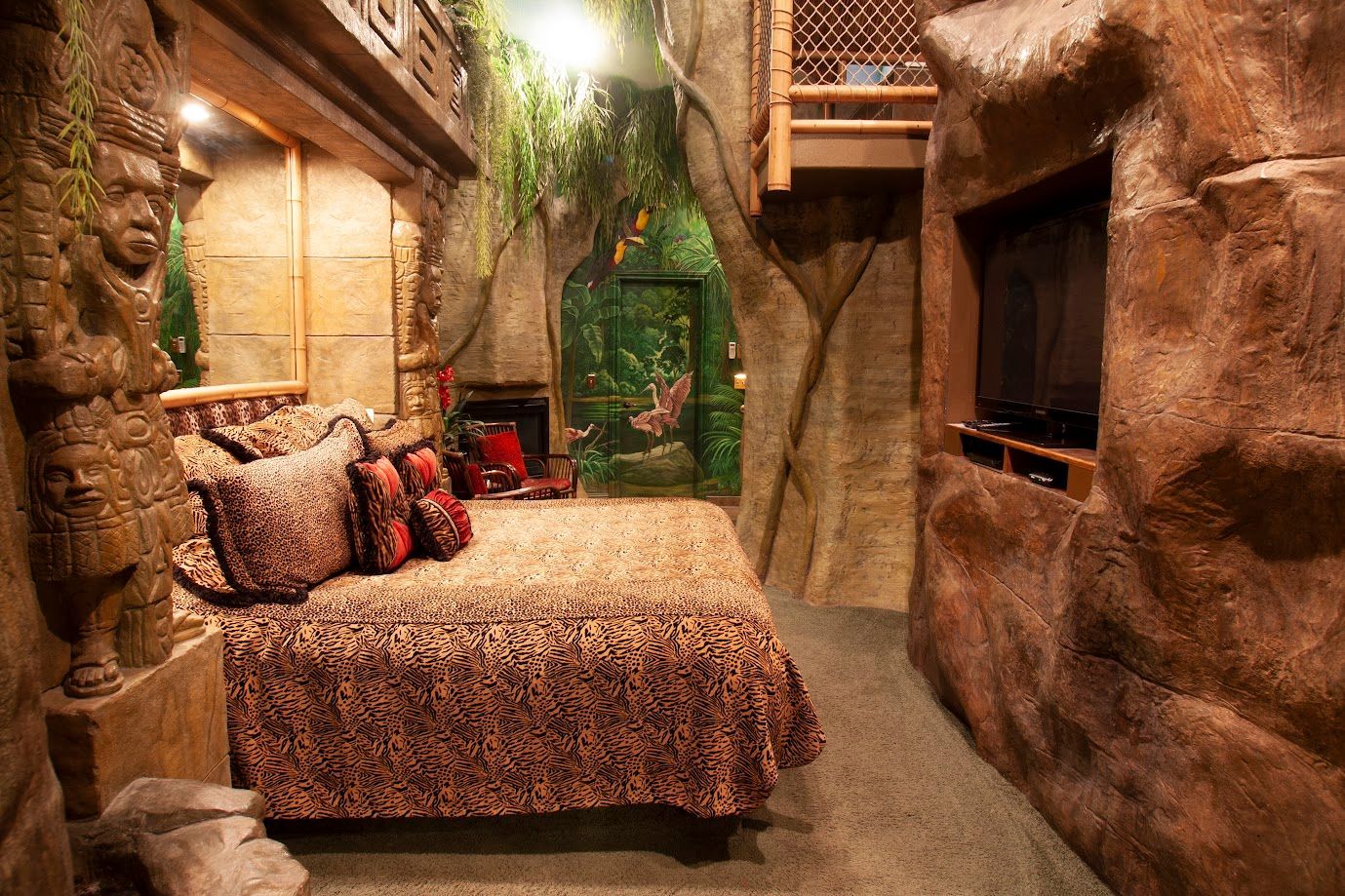 A bedroom with a bed and a television in a cave.