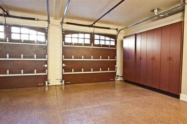 An empty garage with a wooden garage door and red cabinets.