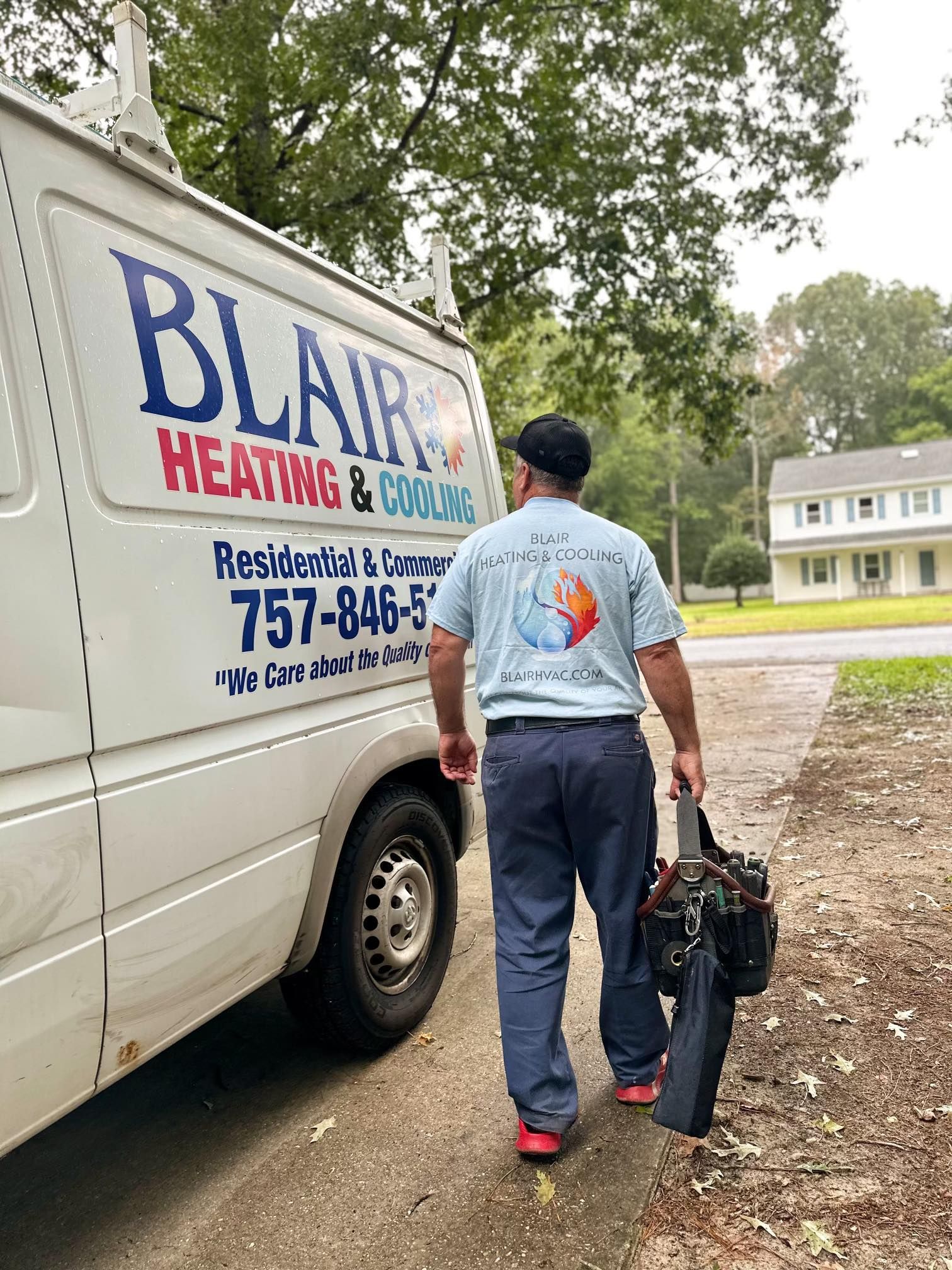 A man is walking towards a blair heating and cooling van.