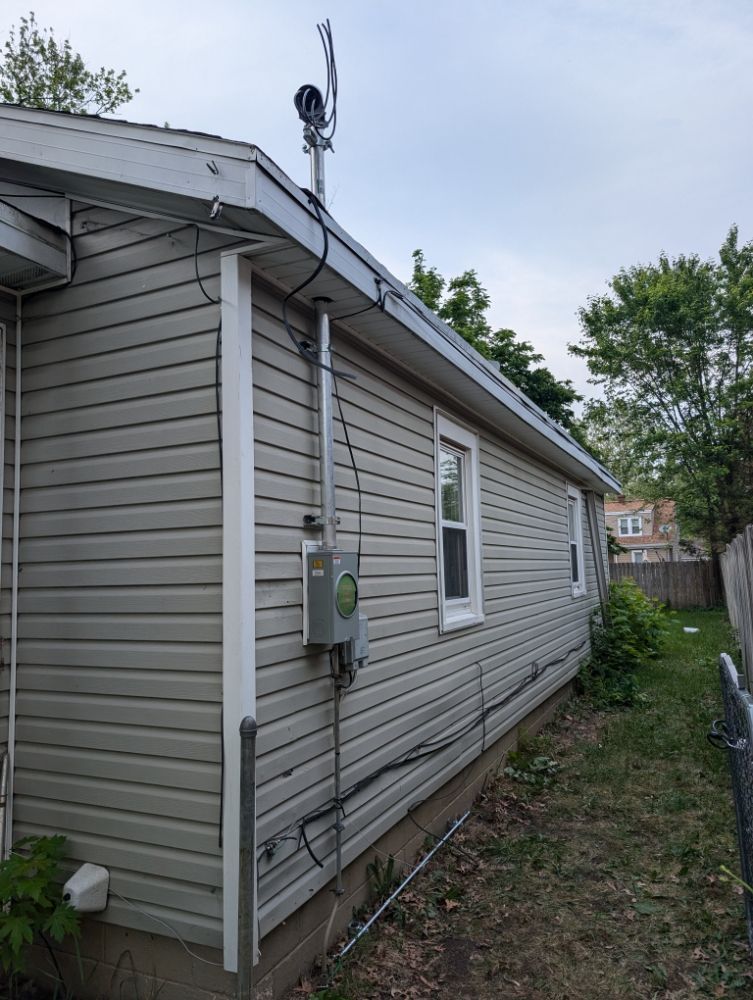 Side view of a house with gray siding, white trim, a power meter, and a satellite dish.