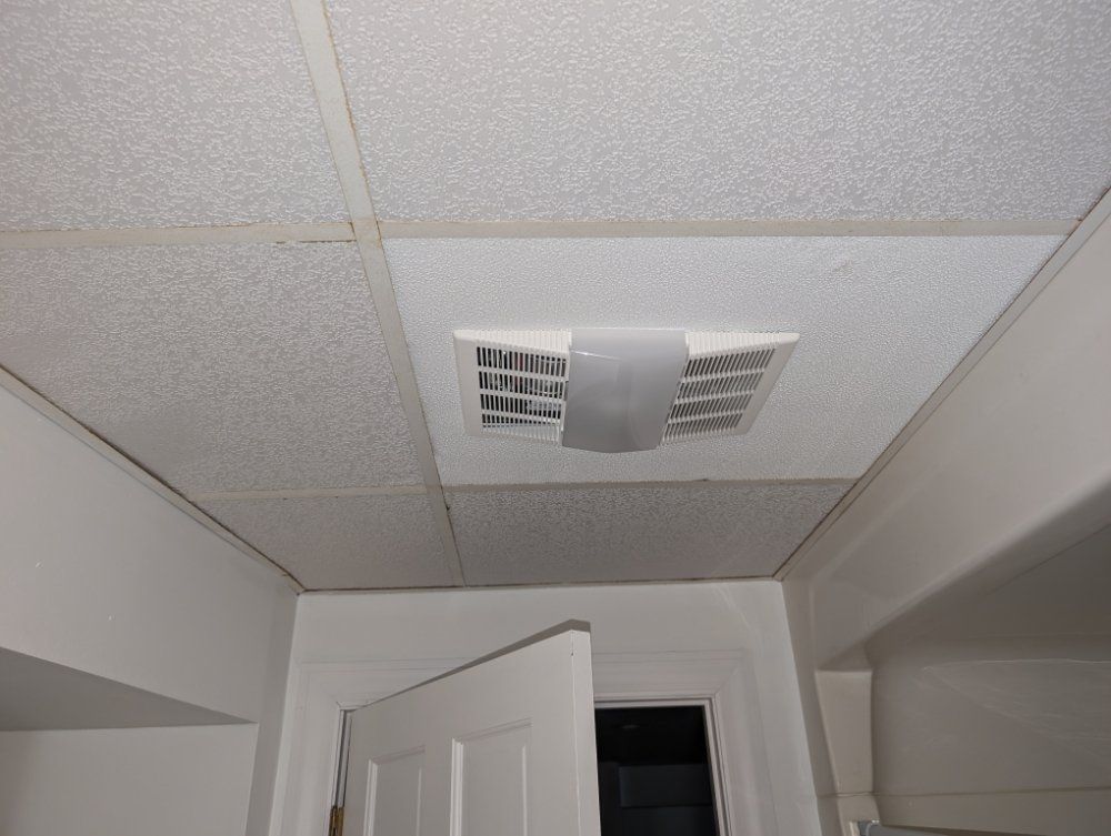 White ceiling with an air vent, a partially open white door, and white walls.