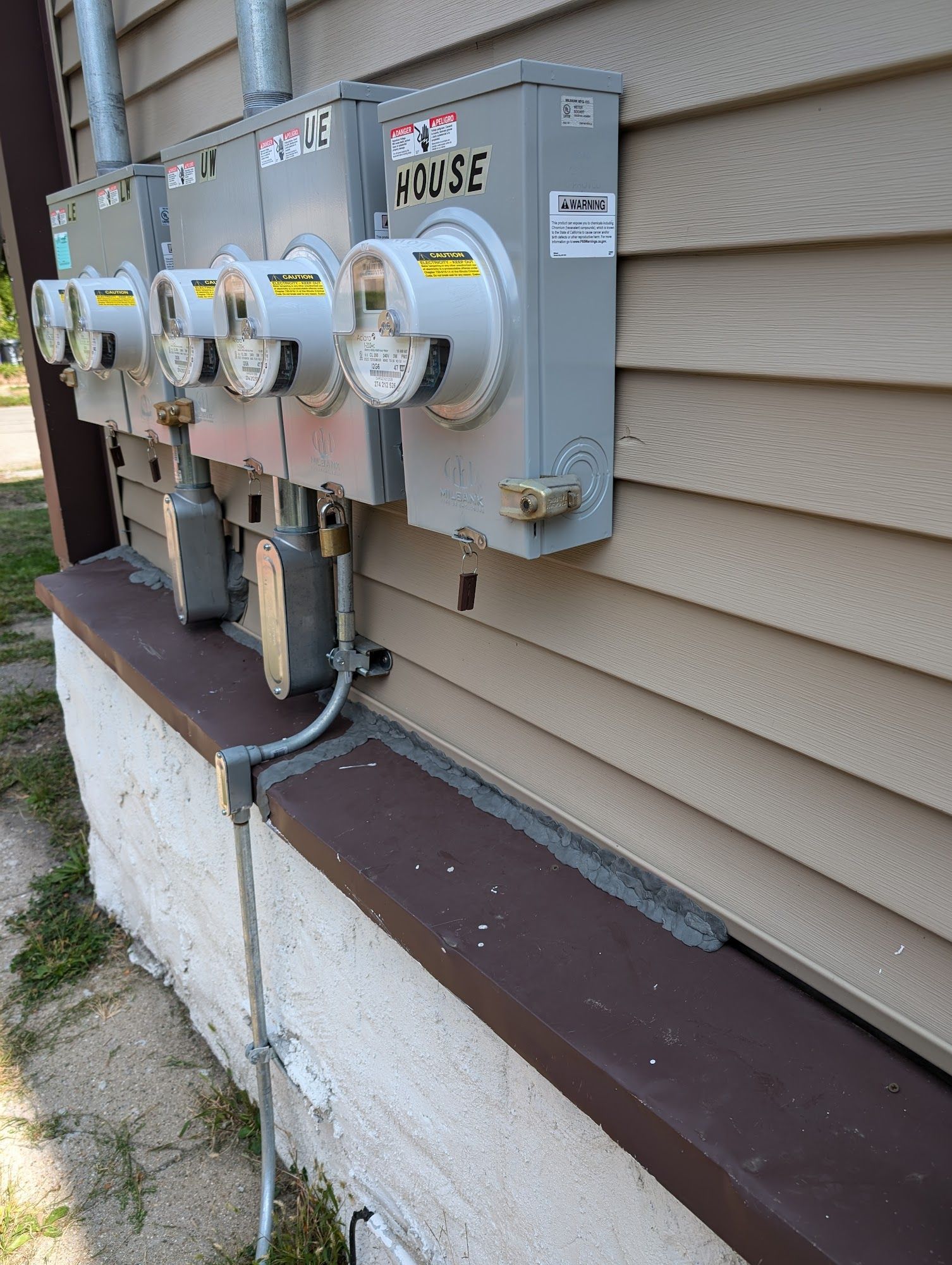 Several electric meters attached to a beige house exterior.
