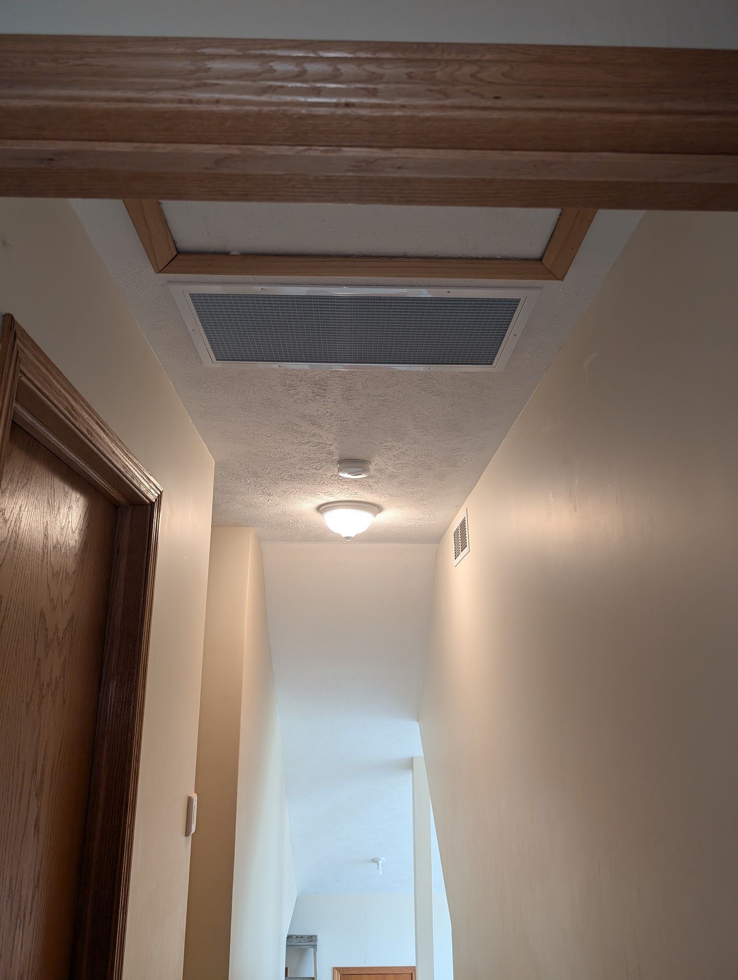 Hallway with drop-down access panel in ceiling; light fixture and doorway visible.