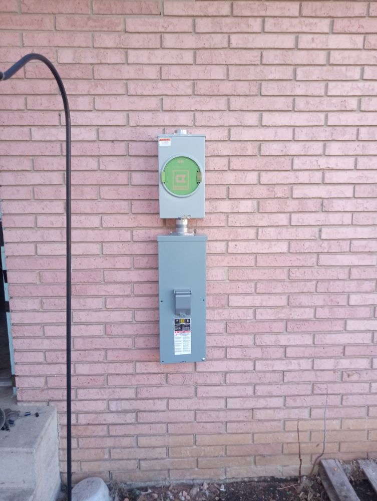 Electrical meter box and breaker box mounted on a brick wall.