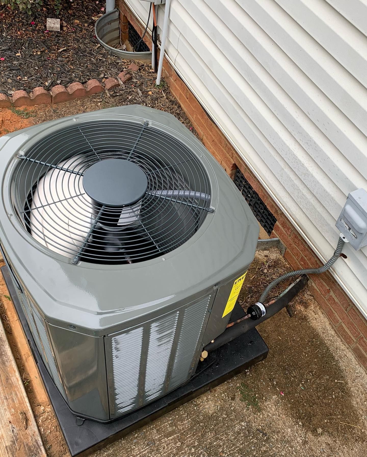 A large air conditioner is sitting on the side of a house.