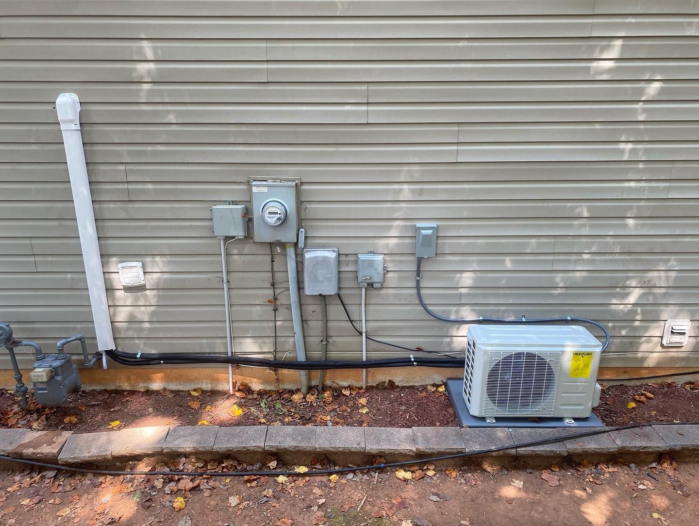 A small air conditioner is sitting on the side of a house.