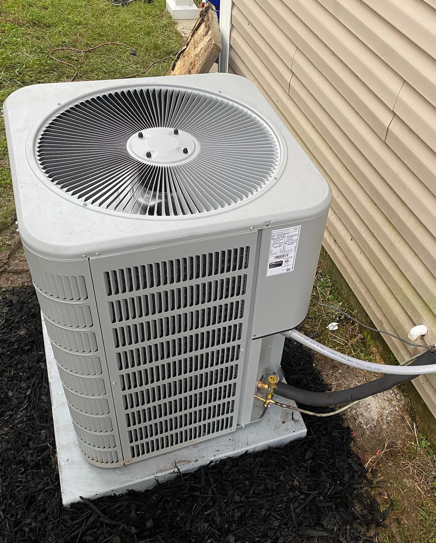 A large air conditioner is sitting on the side of a house.