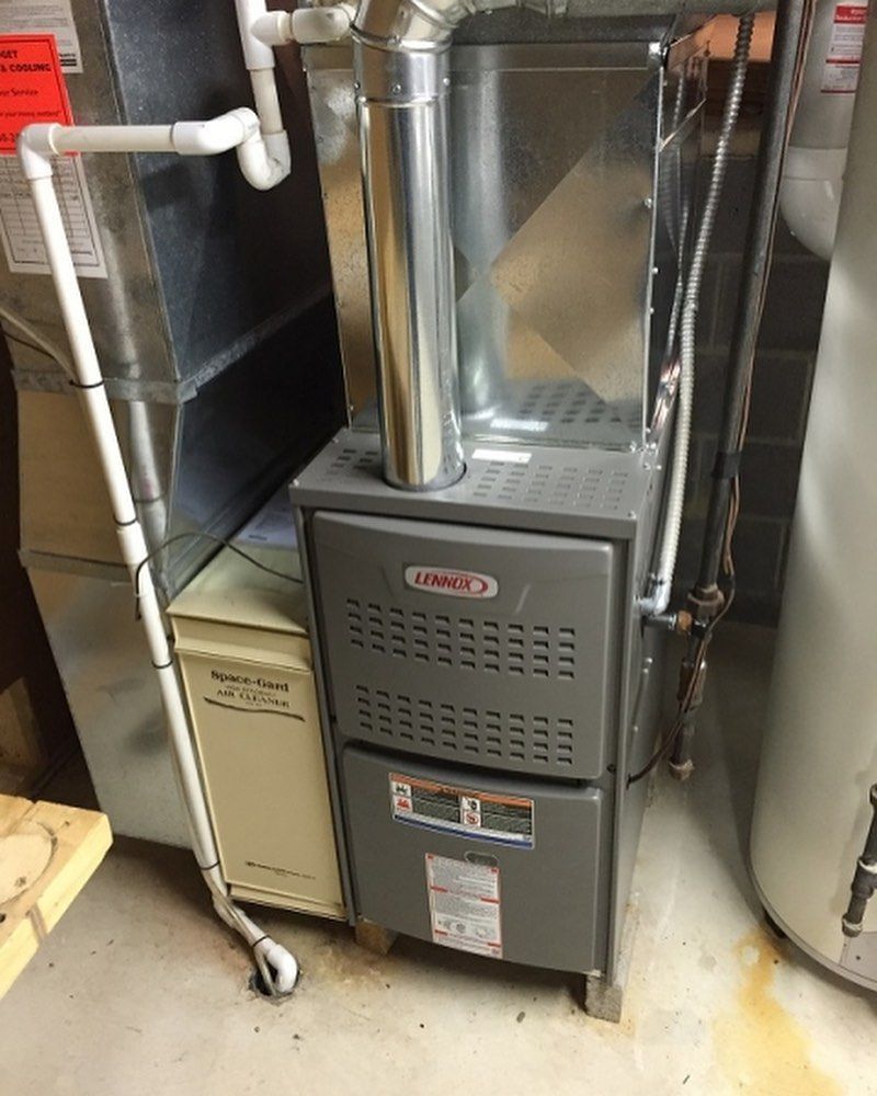 A furnace is sitting in a basement next to a water heater.