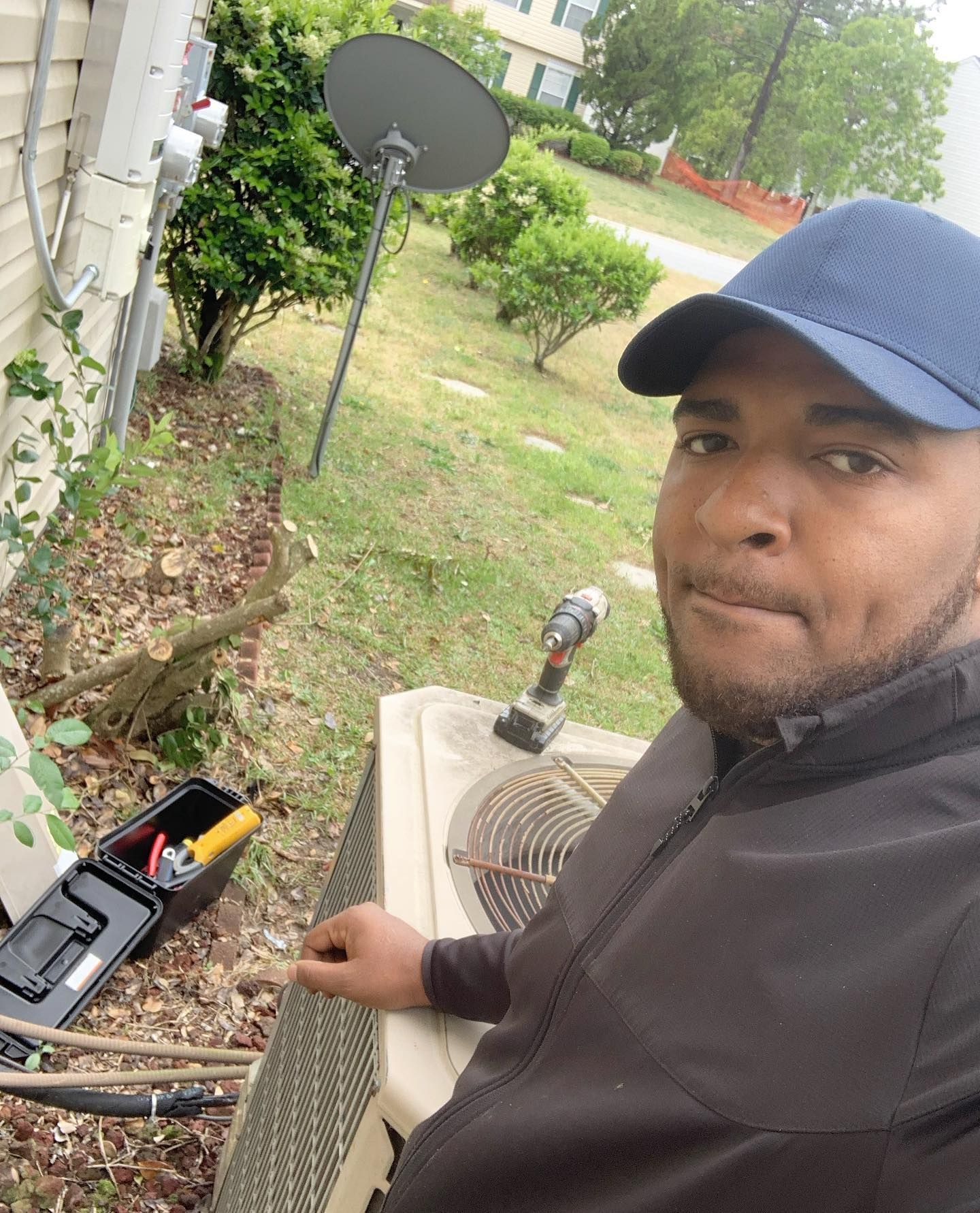 A man in a blue hat is working on an air conditioner.