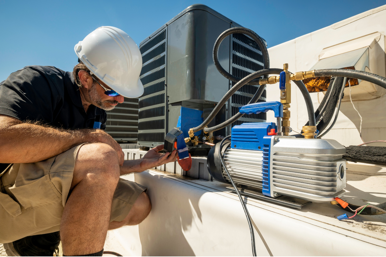 A man is working on an air conditioner on the roof of a building.