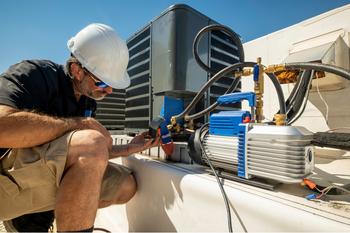 A man is working on an air conditioner on the roof of a building.