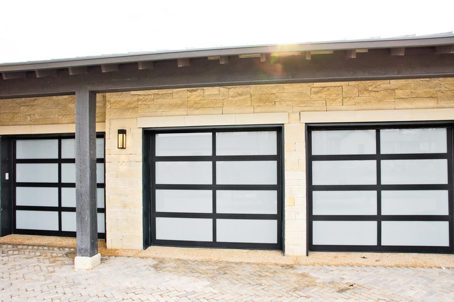 Modern house exterior with three frosted glass garage doors and stone facade