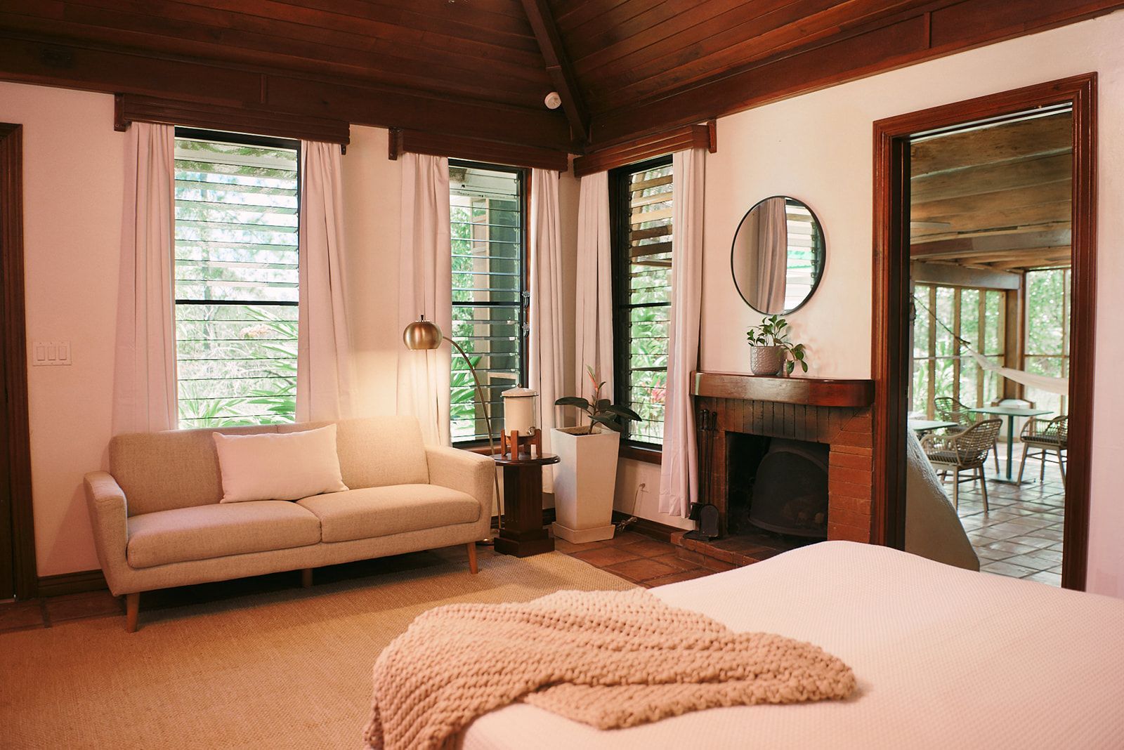 A bedroom with a bed , couch , fireplace and mirror.