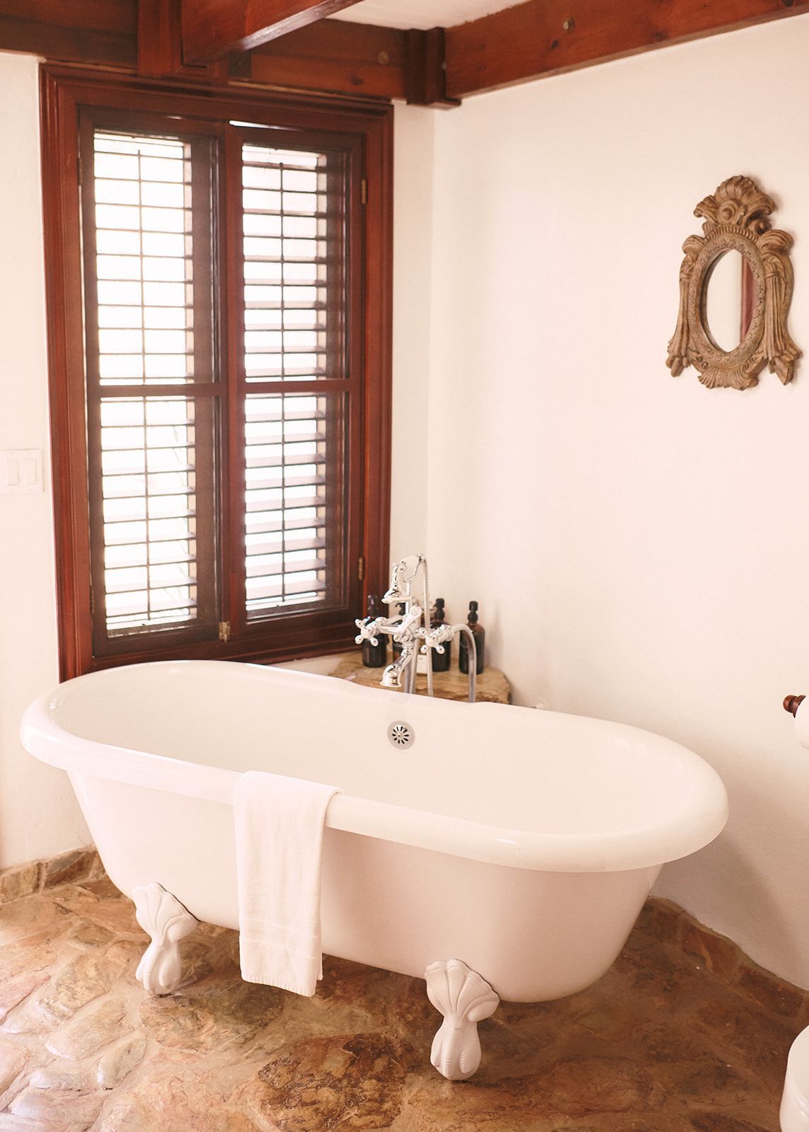 Clawfoot bathtub with views of a stone outdoor shower, creating a natural, spa-like ambiance.