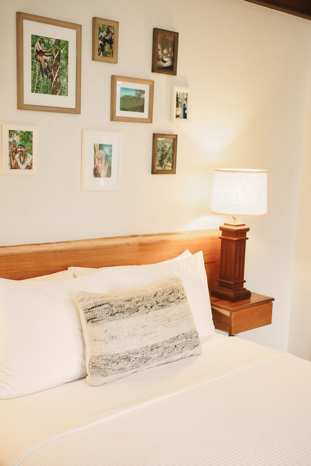 A bedroom with a bed , lamp and pictures on the wall.