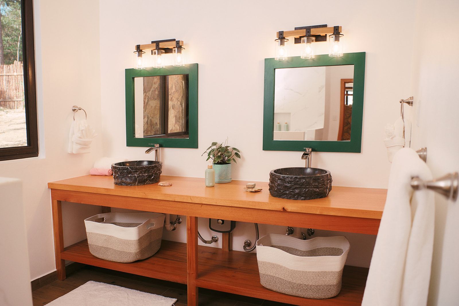 A stylish double-sink vanity in the Valley View Villas with unique stone sinks, wood accents, and soft, elegant lighting.
