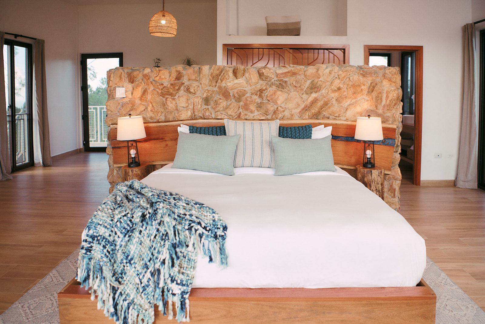 Luxurious king size bed with a stone wall headboard, accented with plush pillows and soft throw blankets in Fire Tower room.